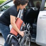 Asian woman folding and lift up wheelchair into her car. Accessibility concept.